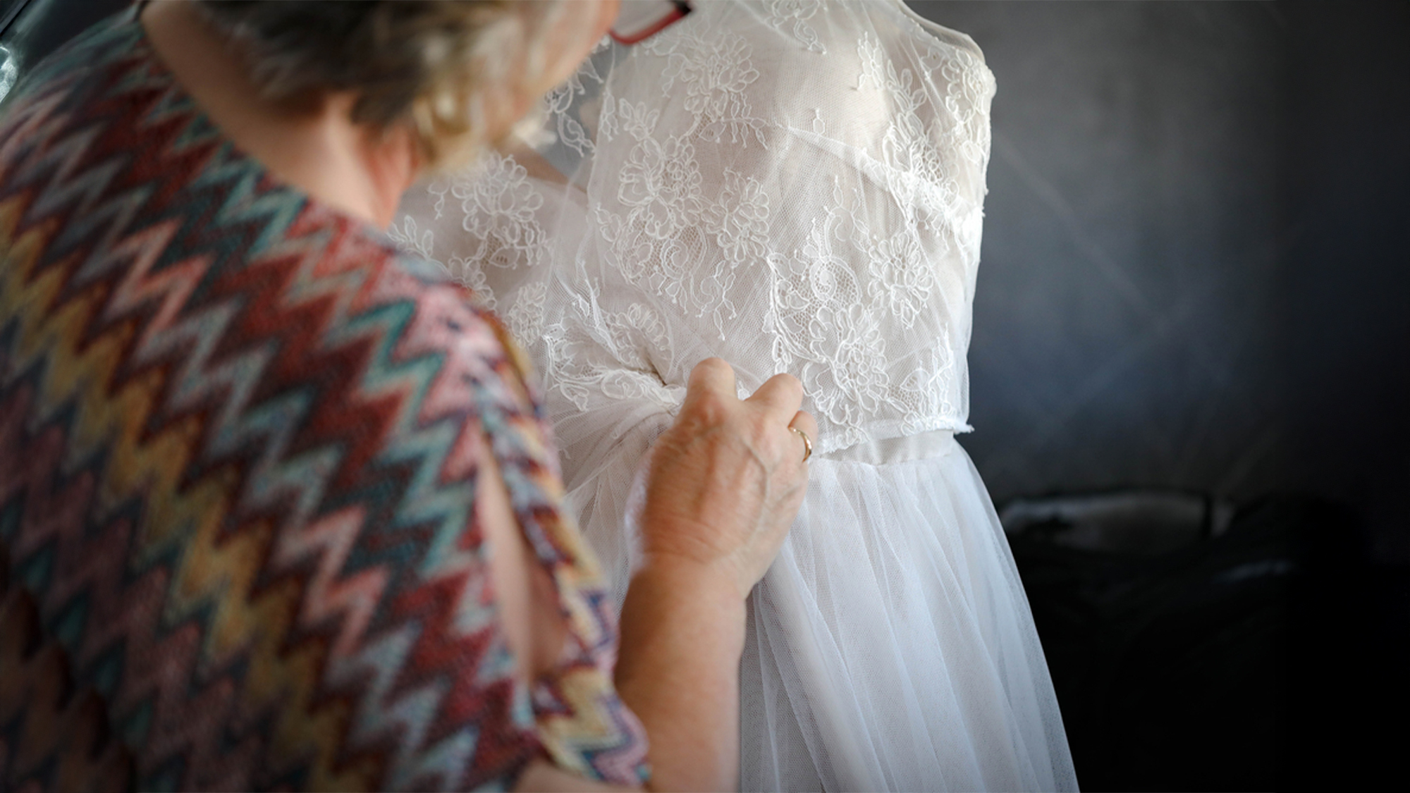 A woman adjusting a white wedding gown